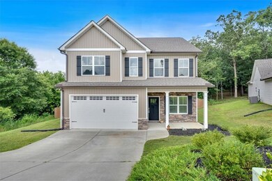 Craftsman inspired home featuring driveway, a front lawn, an attached garage, and stone siding
