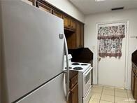 Kitchen with freestanding refrigerator, light tile patterned floors, and white electric range