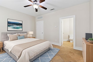 Bedroom with light tile patterned floors, ensuite bathroom, and a ceiling fan