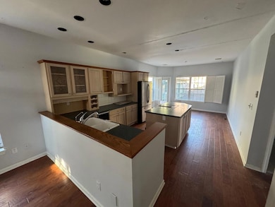 Kitchen with dark wood-style floors, dark countertops, a sink, and freestanding refrigerator
