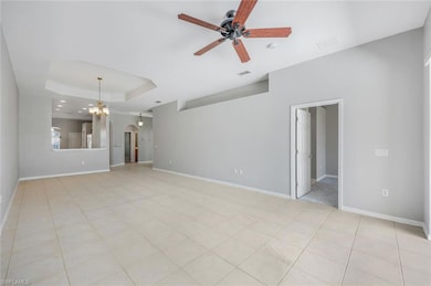 Unfurnished living room with a ceiling fan, a tray ceiling, baseboards, arched walkways, and recessed lighting