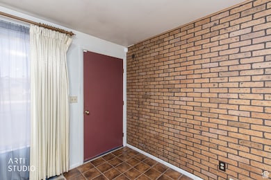 Entrance foyer with brick wall and dark tile patterned floors