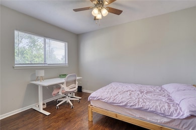Bedroom featuring dark wood-style floors, ceiling fan, and a desk