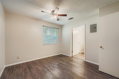 Unfurnished bedroom with a textured ceiling, wood finished floors, electric panel, and a ceiling fan