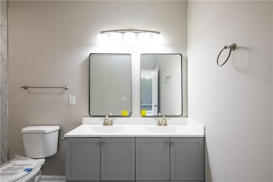Bathroom with double vanity, a sink, and toilet