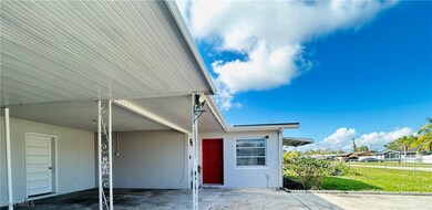 View of exterior entry with a carport and a lawn