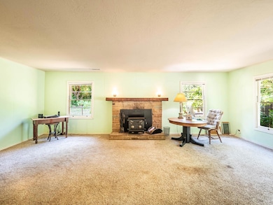 The living room, spacious and softly lit, centers around a wood-burning stove set into a brick hearth.