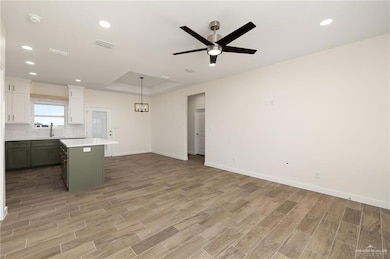 Kitchen featuring green cabinets, white cabinetry, decorative backsplash, light wood finished floors, and recessed lighting