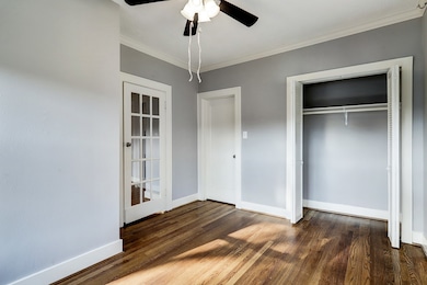 Bedroom #2 with large windows, hardwood floors, crown molding, lighted ceiling fan, and French door opening to the dining room.