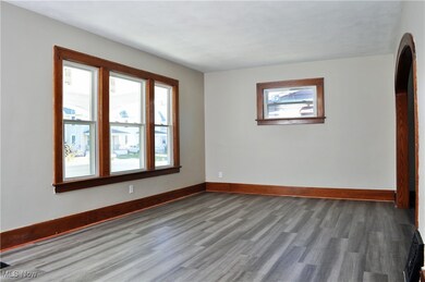 Empty room featuring arched walkways and wood finished floors