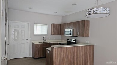 Kitchen with a peninsula, light countertops, stainless steel appliances, modern cabinets, and pendant lighting