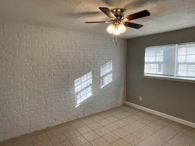 Spare room with light tile patterned floors, brick