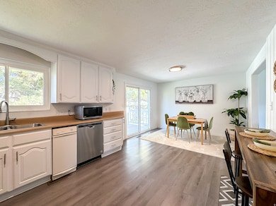 Kitchen featuring white cabinetry, a textured ceiling, light wood-type flooring, appliances with stainless steel finishes, and light countertops