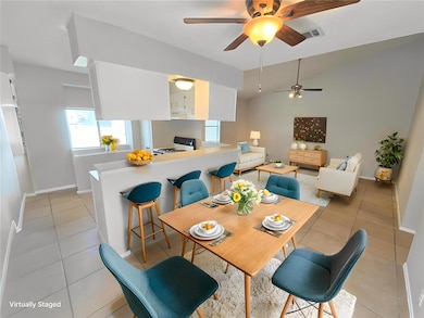 Dining area featuring vaulted ceiling, light tile patterned floors, and ceiling fan