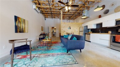 Living area with a wall unit AC, a ceiling fan, ba
