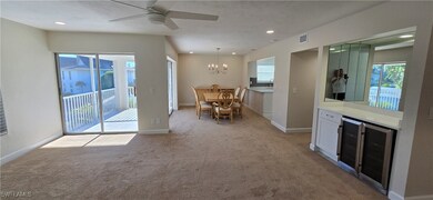 Dining Room with light colored carpet, beverage cooler, a ceiling fan, recessed lighting, and a chandelier