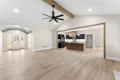 Unfurnished living room featuring arched walkways, recessed lighting, ceiling fan, and light wood-type flooring