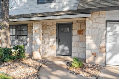 Property entrance featuring stone siding, roof with shingles, and covered porch