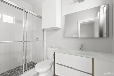 Bathroom with a shower with door, vanity, and toilet