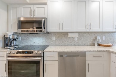 Kitchen with white cabinetry, light stone countert