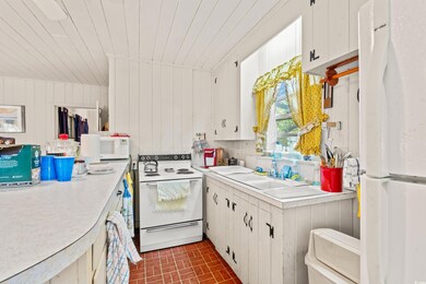 Kitchen with white appliances, brick patterned flooring, light countertops, white cabinets, and wood ceiling