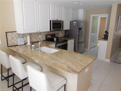 Kitchen featuring stainless steel appliances, a sink, washer and dryer, a peninsula, and backsplash