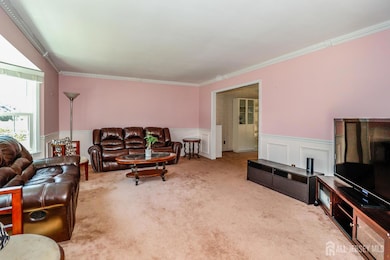 living area featuring a wainscoted wall, ornamental molding, a decorative wall, and carpet flooring