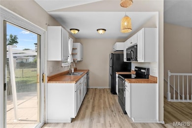 Kitchen featuring white cabinets, black appliances, and light wood finished floors