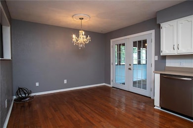 Unfurnished dining area with french doors, dark wood-style flooring, and a chandelier