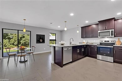 Kitchen featuring stainless steel appliances, a peninsula, recessed lighting, pendant lighting, and light stone counters