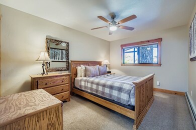 Bedroom with baseboard heating, light colored carpet, and a ceiling fan