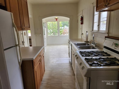 Kitchen featuring white appliances, light countertops, and brown cabinetry
