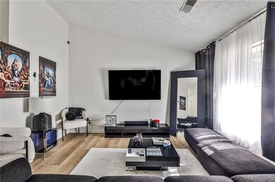 Living area featuring wood finished floors, vaulted ceiling, and a textured ceiling