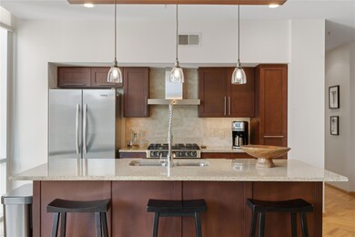 Kitchen featuring a breakfast bar, freestanding refrigerator, light stone counters, hanging light fixtures, and backsplash