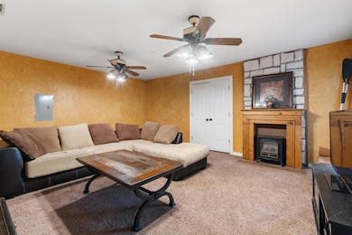 Carpeted living room with electric panel, visible 