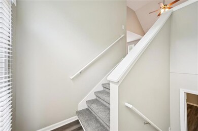 Stairway featuring wood finished floors, ceiling fan, lofted ceiling, healthy amount of natural light, and baseboards