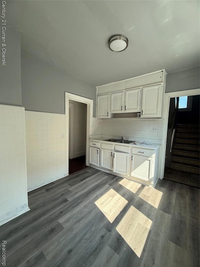 Kitchen with light countertops, dark wood-style floors, white cabinets, and tasteful backsplash