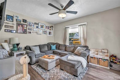 Living room with ceiling fan, hardwood / wood-style flooring, and a textured ceiling