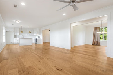 Unfurnished living room with crown molding, a chandelier, light wood-style flooring, ceiling fan, and recessed lighting