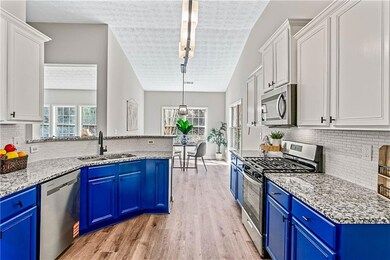 Kitchen with tasteful backsplash, stainless steel appliances, blue cabinets, pendant lighting, and light stone counters