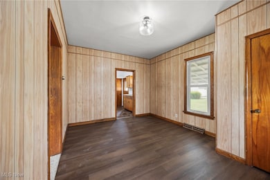 Unfurnished room featuring dark wood-style floors and baseboards