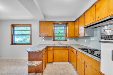 Kitchen with black electric cooktop, light tile patterned flooring, a healthy amount of sunlight, and tasteful backsplash