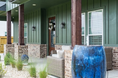 Charming porch with green siding and brick accents