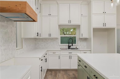 Kitchen featuring white cabinets, light wood-style floors, sink, and tasteful backsplash