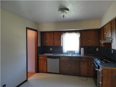 View of kitchen. Eating area is on left with entry