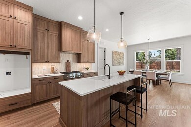 Kitchen with light wood-style floors, light countertops, backsplash, a center island with sink, and recessed lighting
