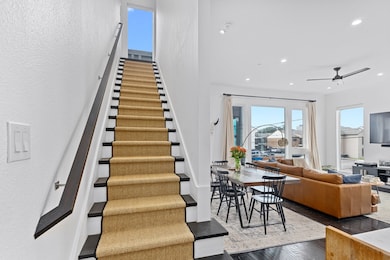 Stairway with hardwood / wood-style floors, a ceiling fan, a textured wall, and recessed lighting