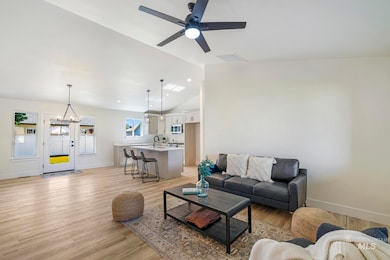 Living area featuring light wood-style floors, ceiling fan, and high vaulted ceiling