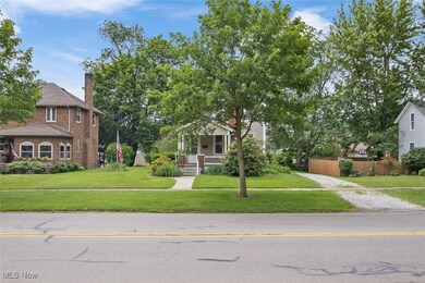 Obstructed view of property with covered porch, a chimney, brick siding, and driveway