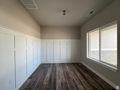 Unfurnished room with dark wood finished floors, a decorative wall, and a wainscoted wall
